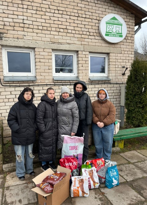 izglītojamās un skolotāja pie dzīvnieku mājas Astes un ūsas